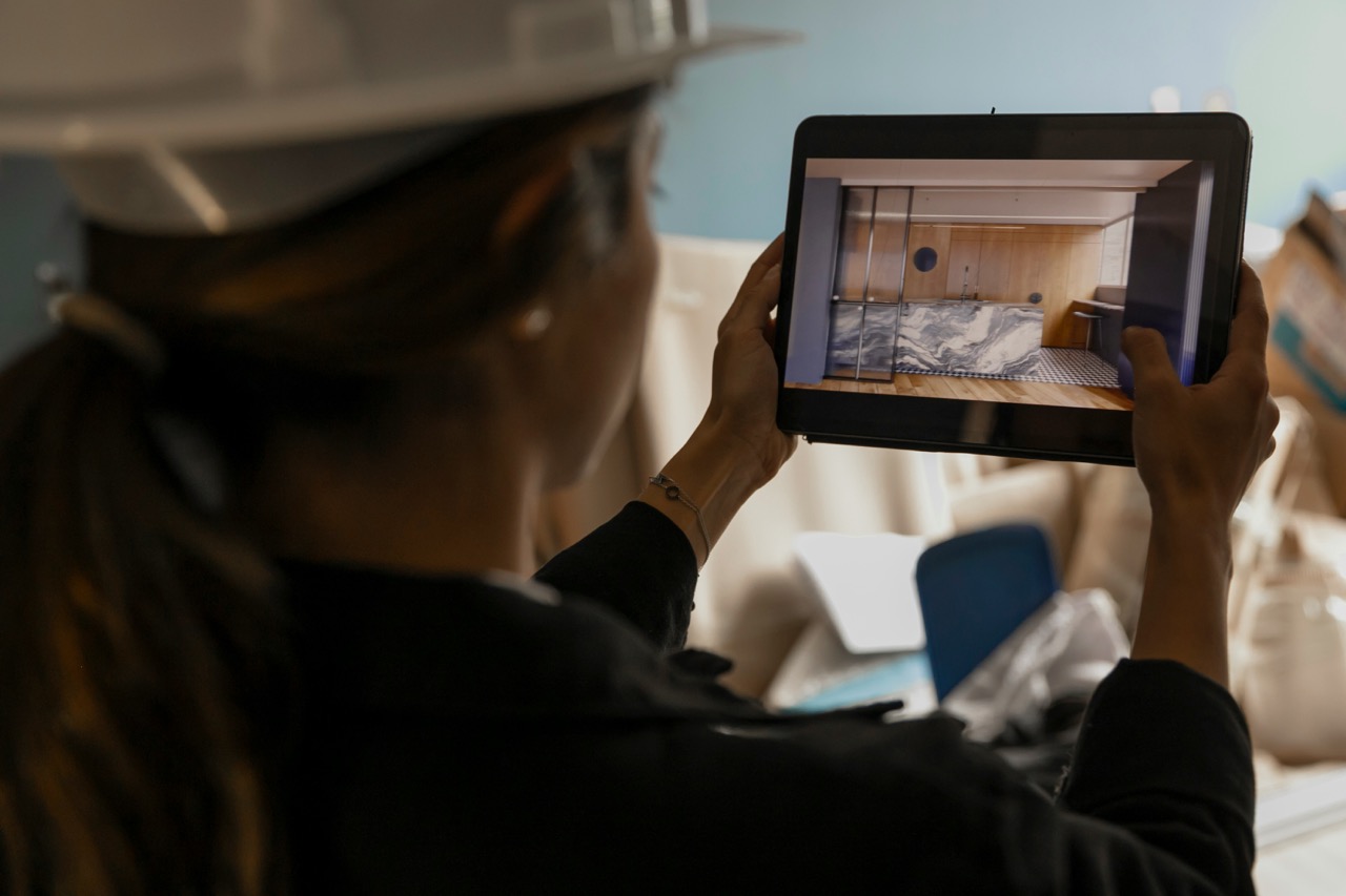 A person wearing a hard hat using a tablet to view a digital image of a room interior with a marble design