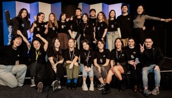 Group photo of smiling Accessibility & Inclusion 2025 volunteers, posing together on stage after a successful event.