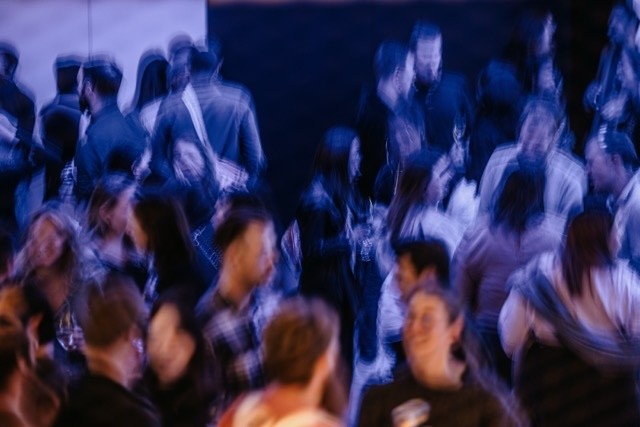 A bustling crowd at a Design Outlook event captured with an artistic, motion-blurred effect, creating a sense of movement and energy in the room.
