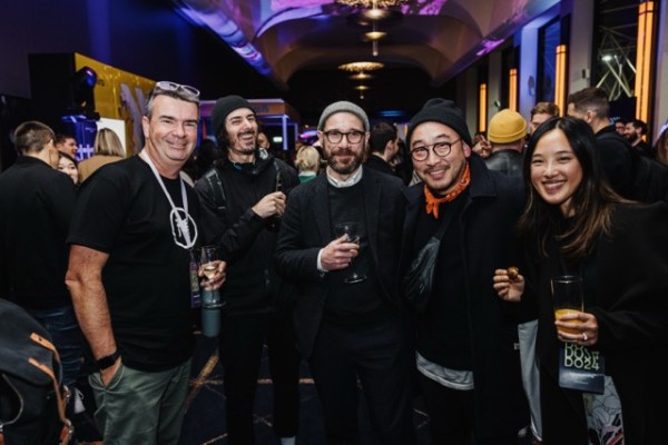 DO24 attendees gathered in a vibrant networking space, smiling and holding drinks, capturing the lively atmosphere of connection and conversation.