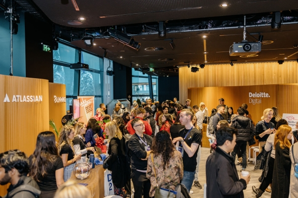 Attendees explore sponsor booths at Design Outlook 2022. The space is buzzing with conversation, with Atlassian, Deloitte Digital, and Bunnings stalls visible.