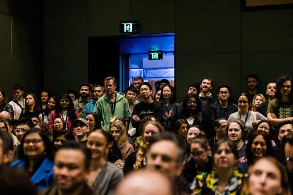 A packed room of attendees at Product Outlook 2025 in Melbourne, with people standing at the back due to high turnout.