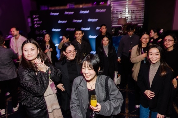 Guests mingle and smile at The Outlook pre-event gathering, enjoying drinks and conversation in front of a branded media wall.