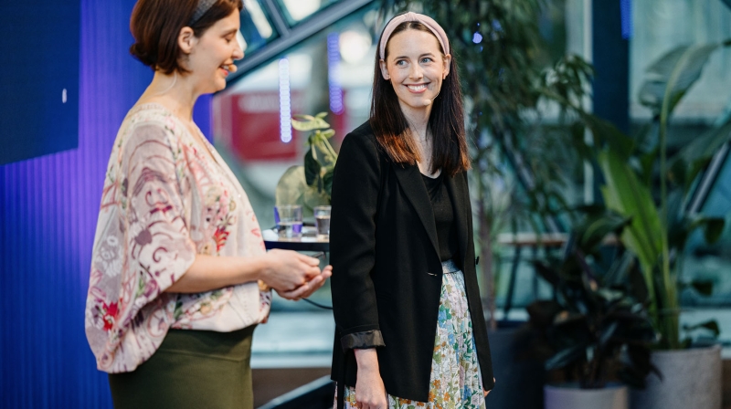 Nicole Austin and Louise Sporton present at Design Outlook 2022. Nicole wears a floral blouse and green skirt; Louise wears a floral skirt and black blazer.