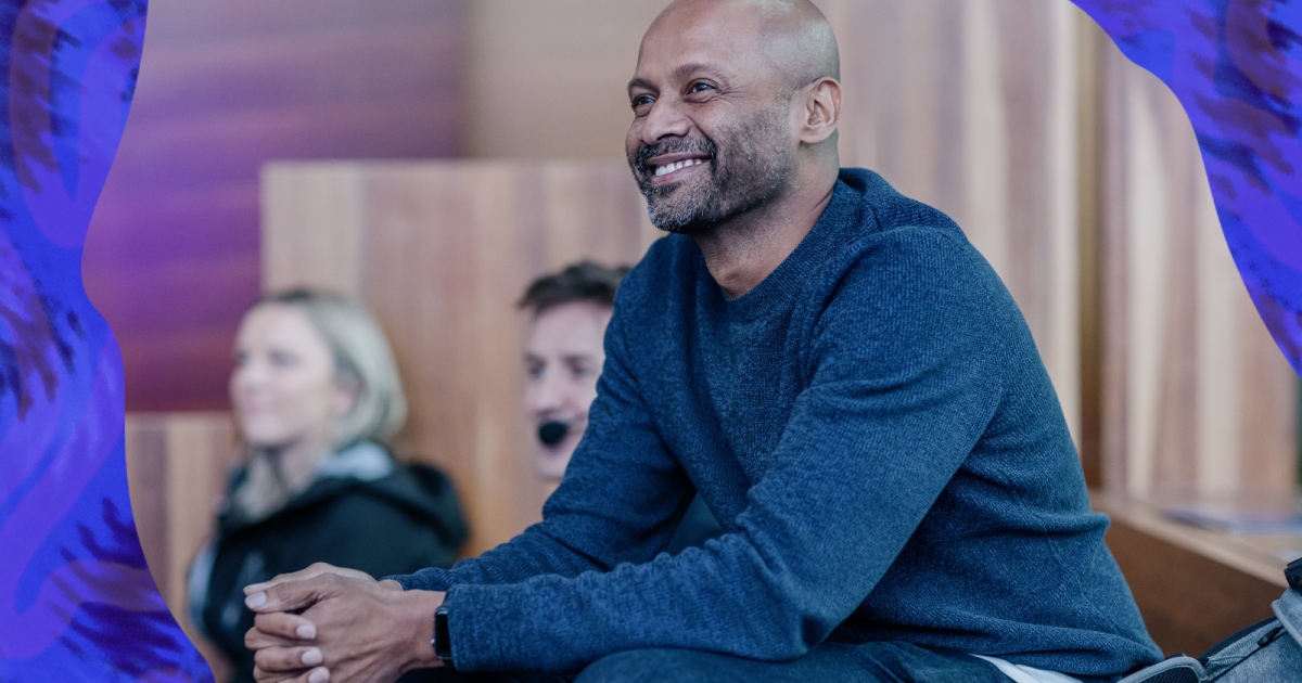 Mathan Ratinam sits by the stage at DO22, smiling at the current presenter