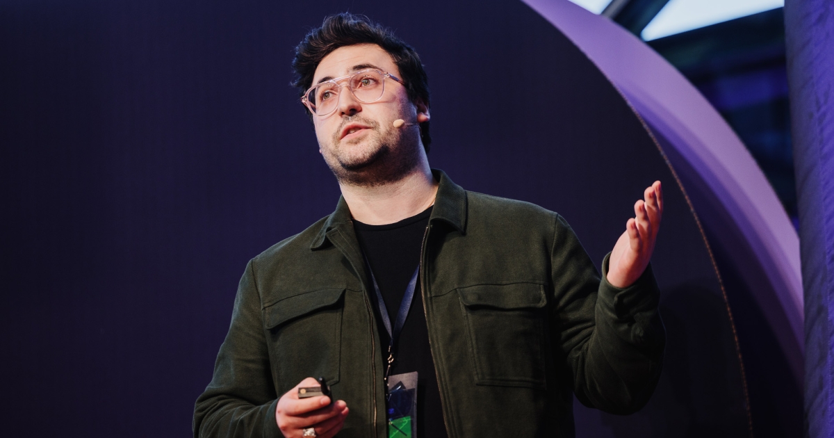 Peter Barber presenting at DO23, gesturing with his hands to the audience